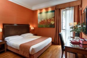 a hotel room with a bed and a desk and a window at Grand Hotel Adriatico in Florence