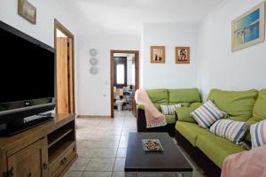 a living room with a green couch and a flat screen tv at Villa Fornell in Conil de la Frontera