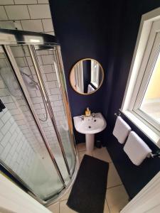 ein Bad mit einer Dusche, einem Waschbecken und einem Spiegel in der Unterkunft Stylish 3 Bedroom Galway House in Galway