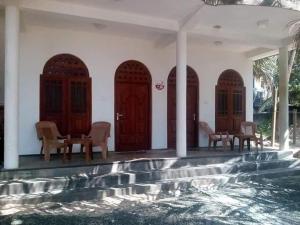 a house with wooden doors and chairs and a swimming pool at Sea Garden Beach Resort in Habaraduwa Central