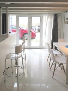a dining room with white chairs and a red car in a parking lot at Appartamento open space in Turin
