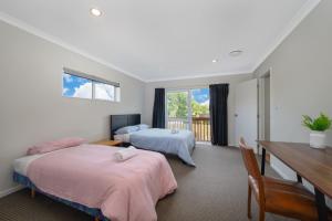 a bedroom with two beds and a desk and a table at Large House. Convenient Location. in Auckland