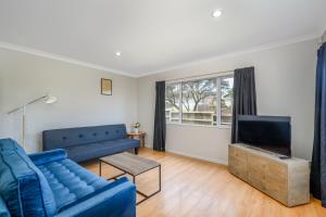 a living room with a blue couch and a tv at Large House. Convenient Location. in Auckland