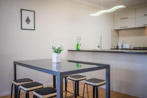 a kitchen with a table and four stools at Large House. Convenient Location. in Auckland