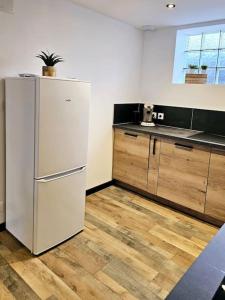 eine Küche mit einem weißen Kühlschrank und Holzböden in der Unterkunft appartement cosy à seloncourt in Seloncourt