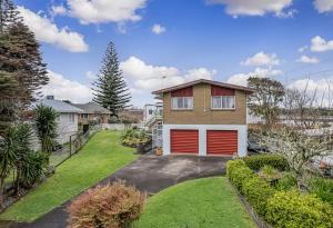 a house with red garage doors in a yard at Large House. Convenient Location. in Auckland