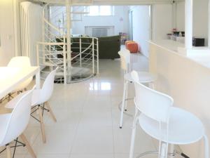 a white kitchen with white chairs and a table at Appartamento open space in Turin