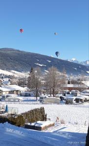 un campo cubierto de nieve con un globo de aire caliente a lo lejos en Familie Fritzenwallner, en Altenmarkt im Pongau