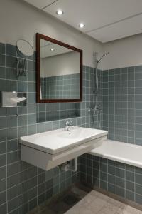 e bagno con lavandino, specchio e vasca. di Helnan Marselis Hotel a Arhus