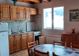uma cozinha com armários de madeira, uma mesa e um frigorífico em Appartement Daniel em Lamoura