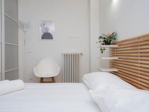 a white bedroom with two beds and a chair at I Host Apartment - Forlanini 1 in Milan