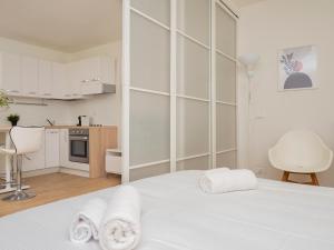 a white bedroom with a white bed and a kitchen at I Host Apartment - Forlanini 1 in Milan