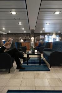 a person sitting on a couch in a waiting room at Helnan Marselis Hotel in Aarhus