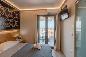 a bedroom with a bed and a tv and a balcony at Zama Suites in Zakynthos Town