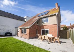 a brick house with a patio with a table and benches at Dalmose in Seaton