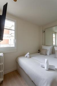 a white bedroom with a bed and a window at The Carla Suite Eiffel Tower View in Paris