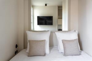 a room with white pillows on a bed with a window at The Carla Suite Eiffel Tower View in Paris +23 photos