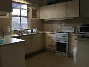 une cuisine avec des armoires blanches et un four à plaques de cuisson dans l'établissement 11 Barrett St, Bungalow QLD 4870, Australia, à East Trinity