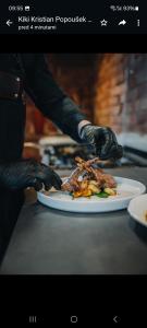 una persona con guantes negros sosteniendo un plato de comida en Garni Hotel Terano, en Maribor