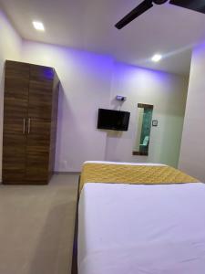 Hotel Blue Wellington - Near Mumbai Airport في مومباي: غرفة نوم بسرير وكابينة وتلفزيون