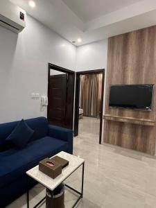 a living room with a blue couch and a tv at بارك بلس للشقق المخدومة in AR Rummanah