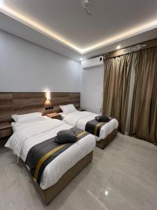 a bedroom with two beds and a window at بارك بلس للشقق المخدومة in AR Rummanah