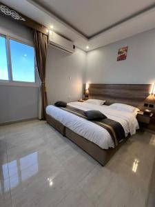 a bedroom with a large bed and a large window at بارك بلس للشقق المخدومة in AR Rummanah