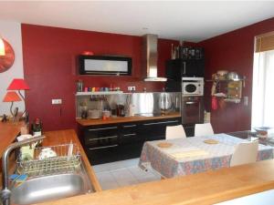 a kitchen with red walls and a table and a sink at MAISON CREUZIER - Vichy à 5min - Jardin - BBQ - Calme in Creuzier-le-Vieux