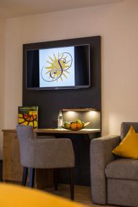 ein Wohnzimmer mit einem Tisch und einem TV an der Wand in der Unterkunft Hotel-Gasthof zur Sonne in Pappenheim