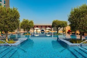 a large swimming pool with trees and blue water at Aloft Abu Dhabi in Abu Dhabi