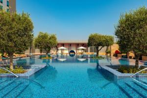duży basen z drzewami i niebieską wodą w obiekcie Aloft Abu Dhabi w Abu Zabi