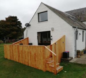 a house with a wooden fence in front of it at Locheil Apartment in Boat of Garten