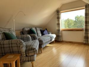 uma sala de estar com dois sofás e uma janela em Locheil Apartment em Boat of Garten
