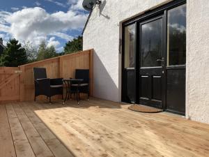 a patio with a table and chairs on a wooden deck at Locheil Apartment in Boat of Garten