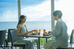 Um homem e uma mulher sentados à mesa com comida. em Shimoda Prince Hotel em Shimoda