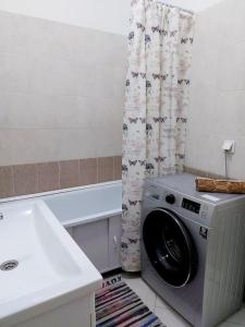 eine Waschmaschine im Bad neben einem Waschbecken in der Unterkunft ЖК Novella in Almaty