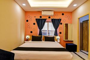 - une chambre dotée d'un lit avec un mur orange dans l'établissement Emerald Inn, à Bhubaneswar