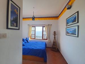 Un dormitorio con una cama azul y una ventana en Peace Dragon Lodge en Pokhara