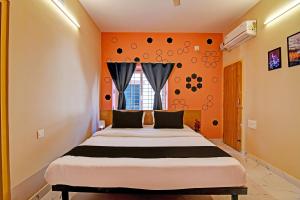 a bedroom with a bed with an orange wall at Emerald Inn in Bhubaneshwar