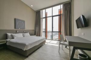 a bedroom with a bed and a desk and a window at PlayStaytion Damansara by RBNB in Damansara Perdana