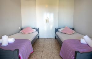 two beds in a room with pink and purple sheets at Kamara Apartments in Alikanas