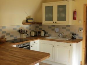 una cucina con mobili bianchi e un lavandino di Sycamore Cottage a Boat of Garten Altre 5 foto