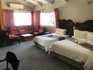 a hotel room with two beds and a couch at Janke Guest House in Kuruman
