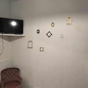 a white wall with clocks and a chair in a room at Le Nid Douillet Baroque Linge fourni in La Bourboule