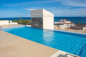 uma piscina com o oceano ao fundo em A Cozy Two Bedroom Sea View Apartment With a Pool and 3 Beds em Mombaça