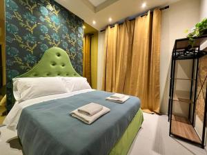 Schlafzimmer mit einem Bett mit grünem Kopfteil in der Unterkunft HomingPisa - Gemini One in Pisa