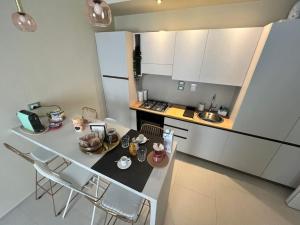 a kitchen with white cabinets and a table and chairs at HomingPisa - Gemini One in Pisa