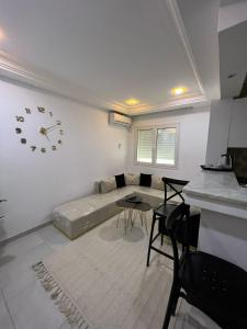 a living room with a couch and a clock on the wall at Appartement de la joie in El Aouina