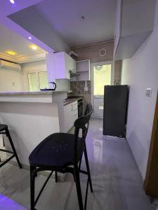 a kitchen with a black chair and a refrigerator at Appartement de la joie in El Aouina