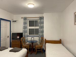 a bedroom with two beds and a table and a window at Coastguard Lodge Hostel at Tigh TP in Dingle
